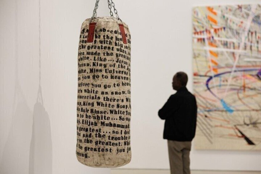A person observing a hanging text piece in an art gallery. 4