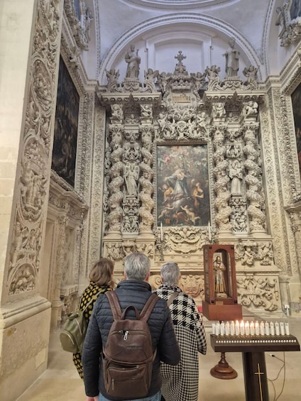 An ornate church interior with detailed sculptures and a central painting. 5