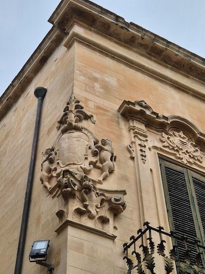 A building facade with ornate stone carvings and a metal gate. 2