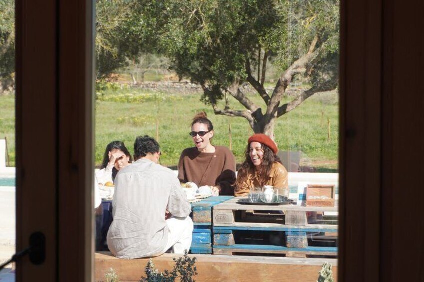 A group of people sitting at an outdoor table with a view of a tree and grass. 3