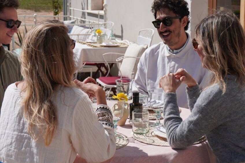 A group of people sitting at an outdoor table with drinks and a bottle of water. 1