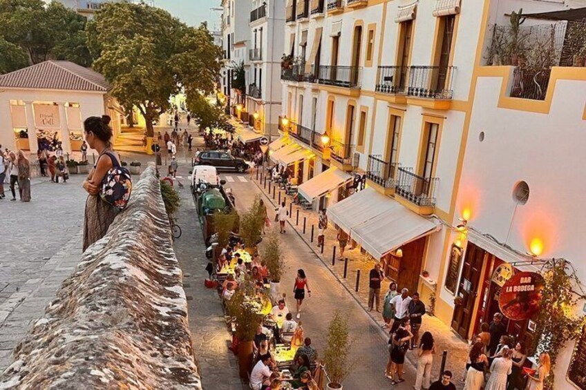 A bustling street with cafes, pedestrians, and parked cars. 3