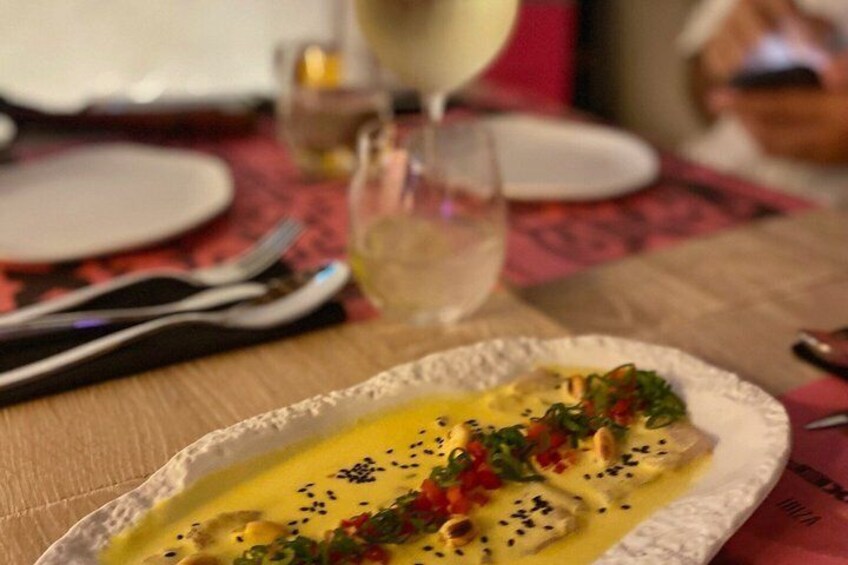 A plate of food with a creamy sauce, garnished with red peppers and black seeds. 2