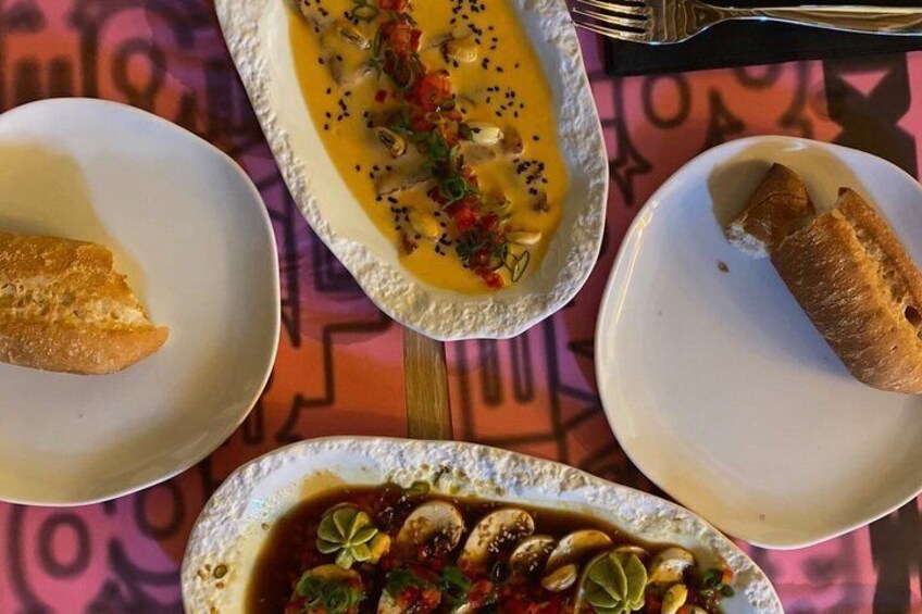 Three plates of food with bread on a tablecloth. 1