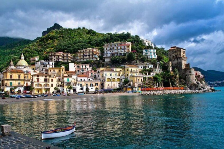 A coastal town with colorful buildings, a boat on the water, and a castle on a hill. 2