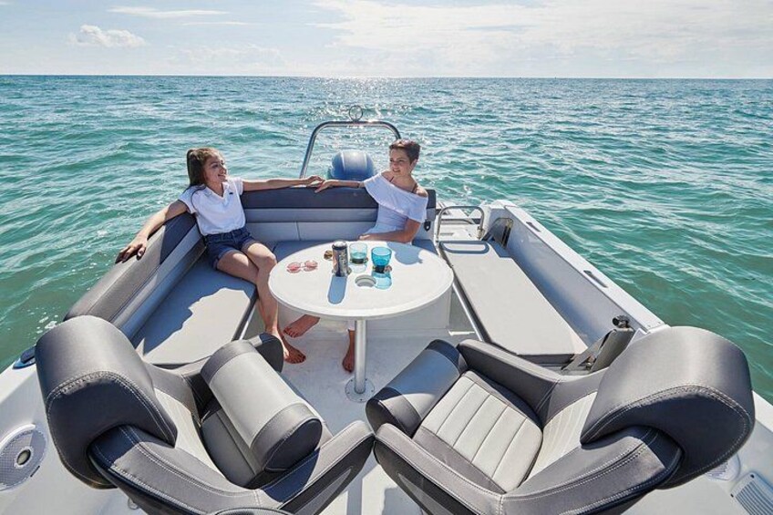 A boat with two people sitting at a table, surrounded by cushioned seating. 5