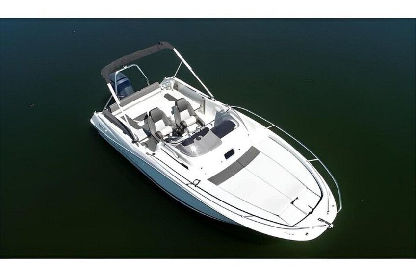 A white motorboat with a canopy, two seats, and a small cabin, floating on calm water. 2