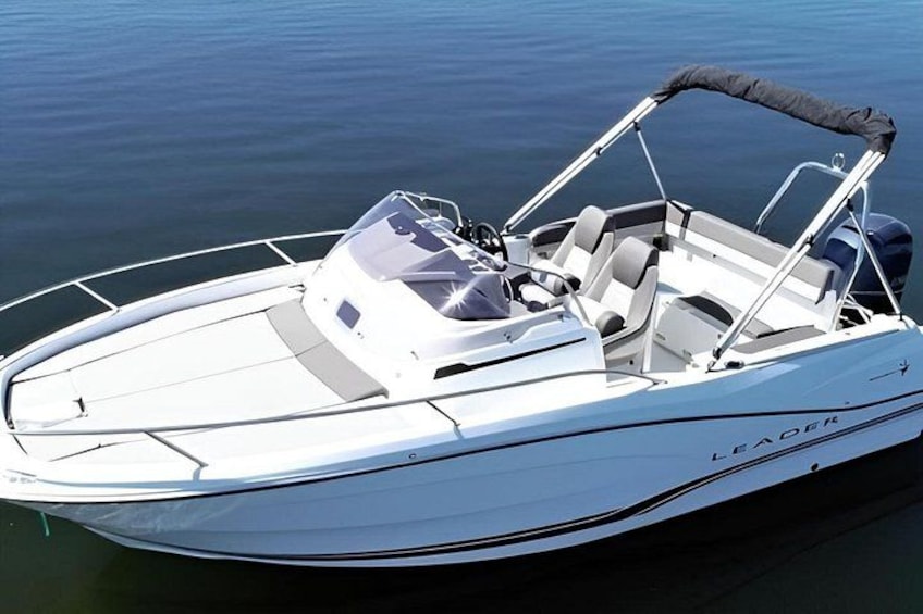 A white speedboat with a canopy, named 'LEADER,' on calm water. 3