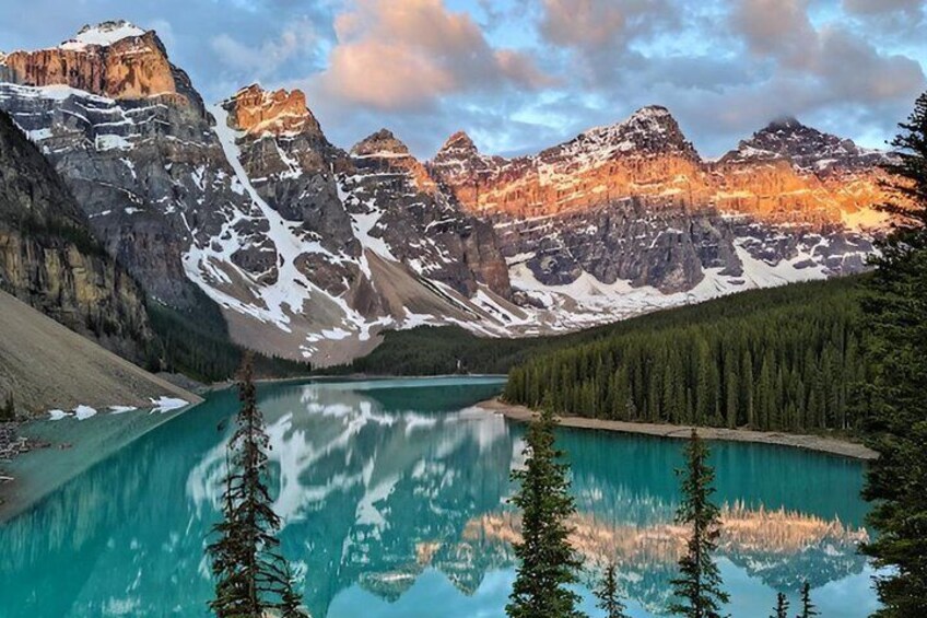 A mountain lake with reflections, surrounded by forest and snow-capped peaks. 5