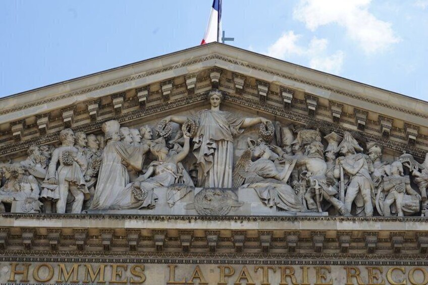 A detailed stone relief on a building facade with inscriptions and figures. 5