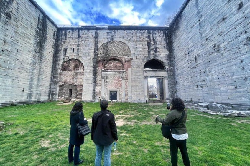 A courtyard with a large brick building featuring arched doorways and a central entrance. 2