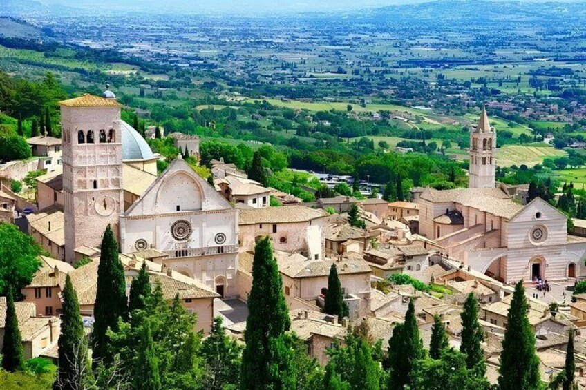 A historic town with prominent churches, a bell tower, and surrounding greenery. 2