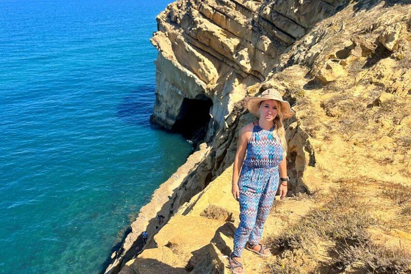A person standing on a rocky cliff by the sea. 5