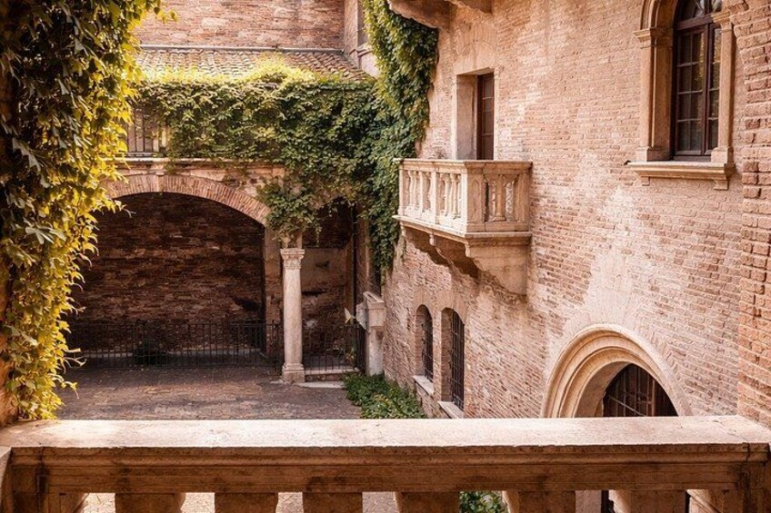 A courtyard with a brick building, an arched stone bridge, and a wooden railing. 5