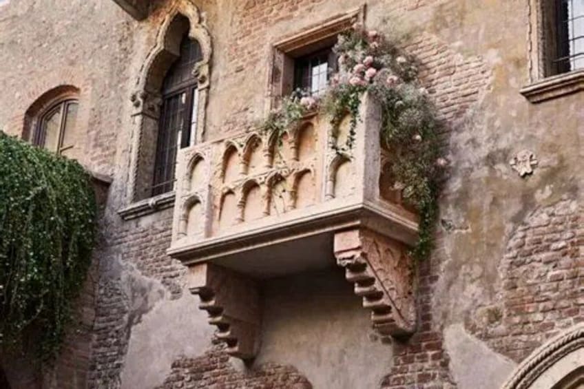 A historic building with a decorative balcony and ivy. 2