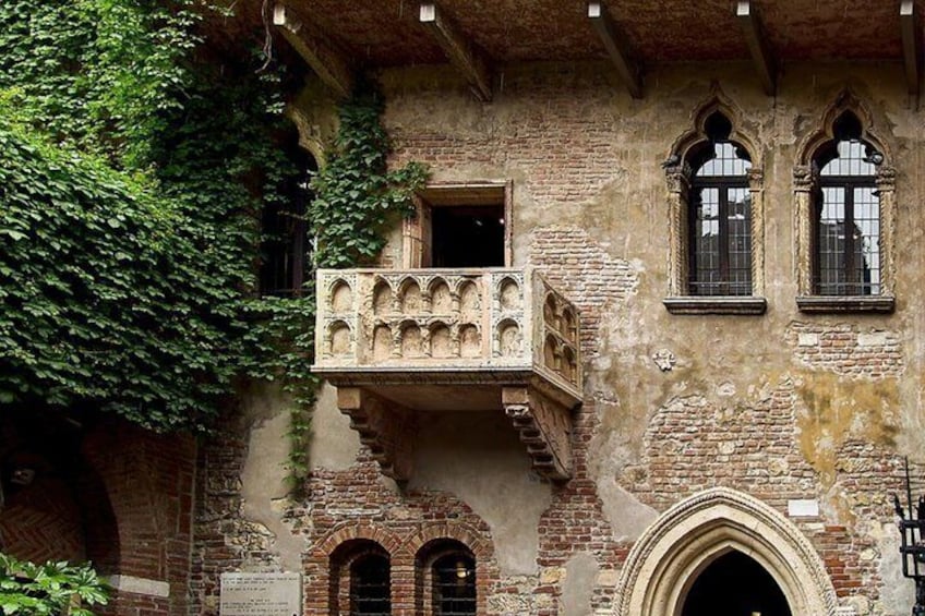 A historic building with a balcony, arched windows, and ivy-covered walls. 3