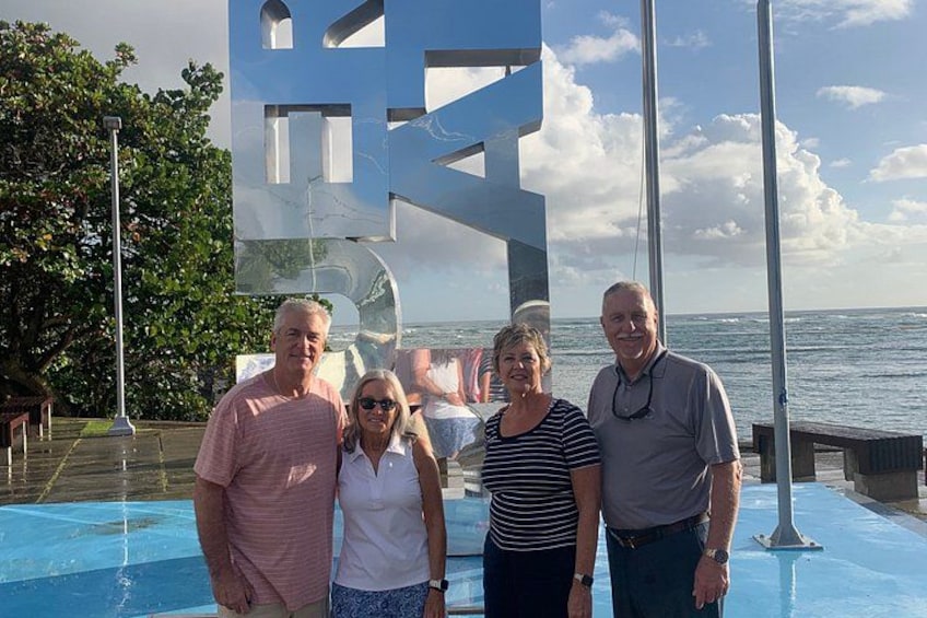 A group of people standing by a pool with a large sculpture in the background. 1