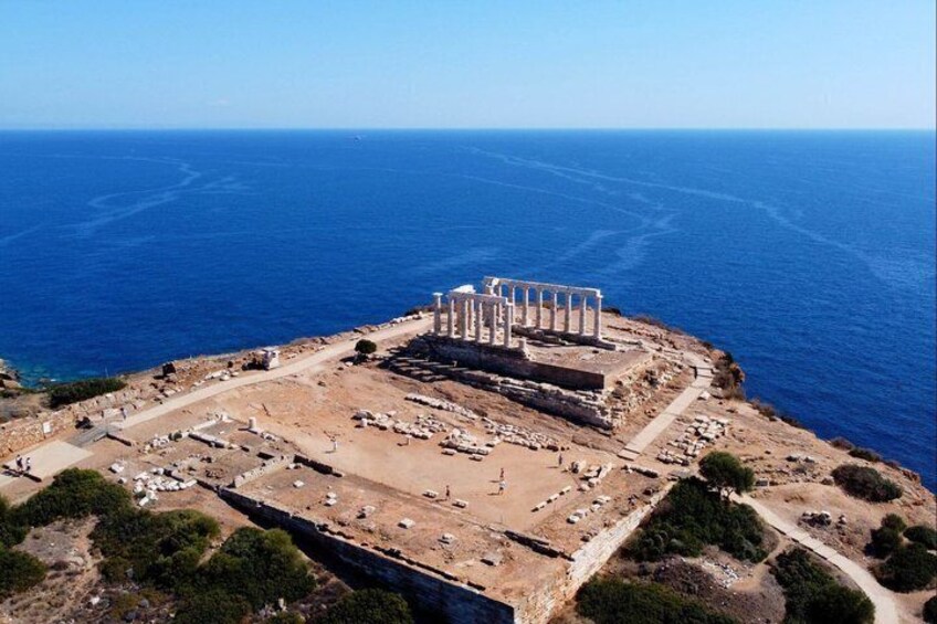An ancient ruin with columns and a surrounding area with pathways and scattered stones. 4
