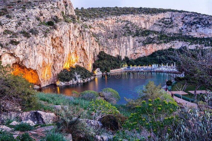 A rocky cliff, a calm lake, and a small island with buildings. 1
