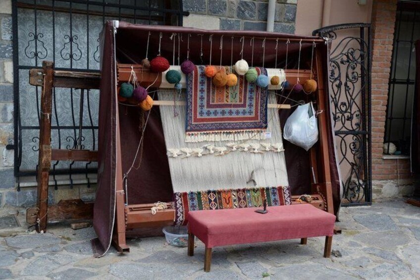 A wooden loom with colorful textiles and yarn balls. 3