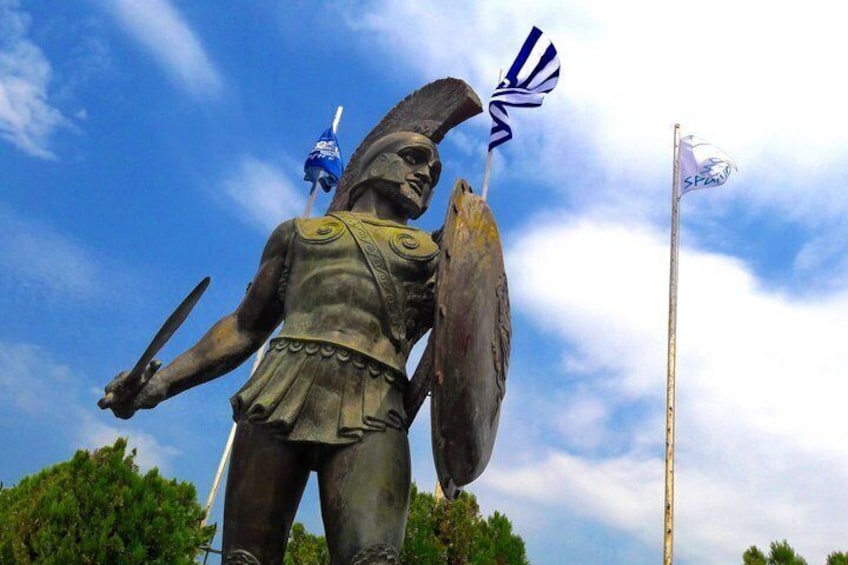 A statue of a warrior holding a sword and shield, with a flag in the background. 1