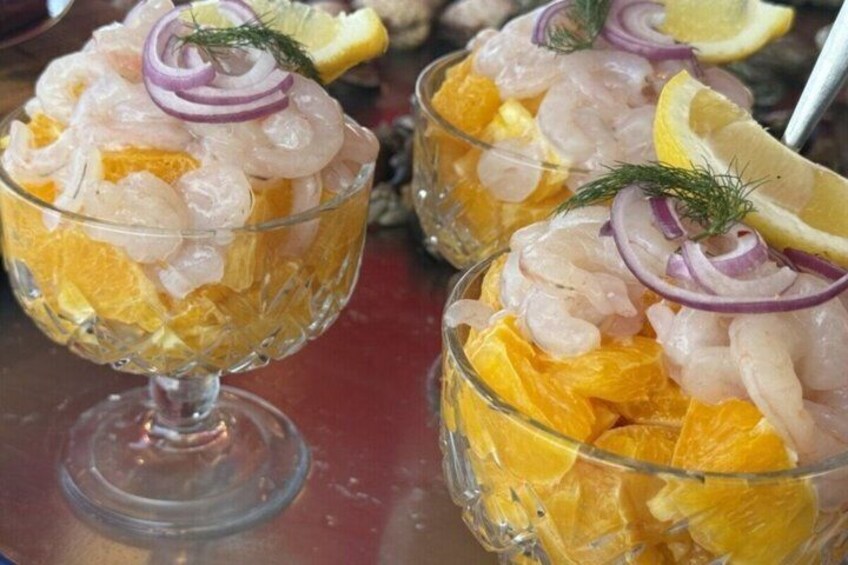 A dish with shrimp, orange segments, and a garnish of dill and red onion. 5