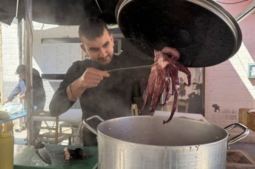 A person cooking octopus over a large pot. 1