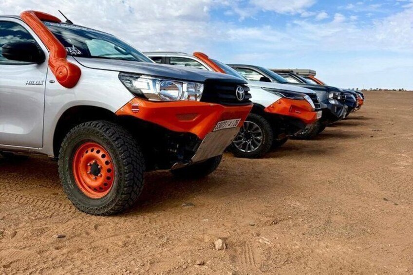 A row of off-road vehicles parked on a dirt surface. 4