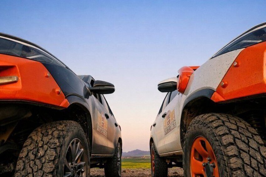 Two off-road vehicles parked on a dirt road with a clear sky. 5