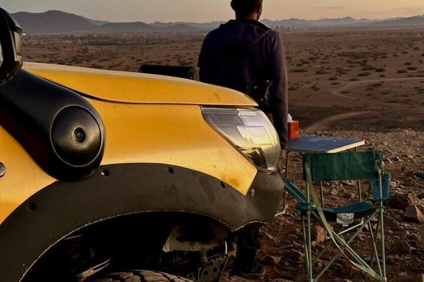 A person standing next to a yellow vehicle in a desert landscape. 2