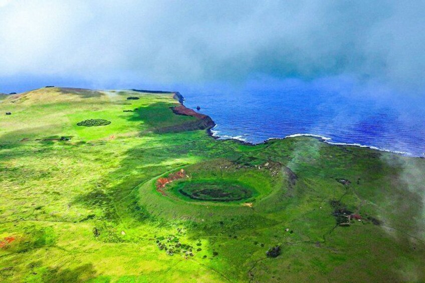 A coastal landscape with green fields, a circular structure, and the ocean. 5