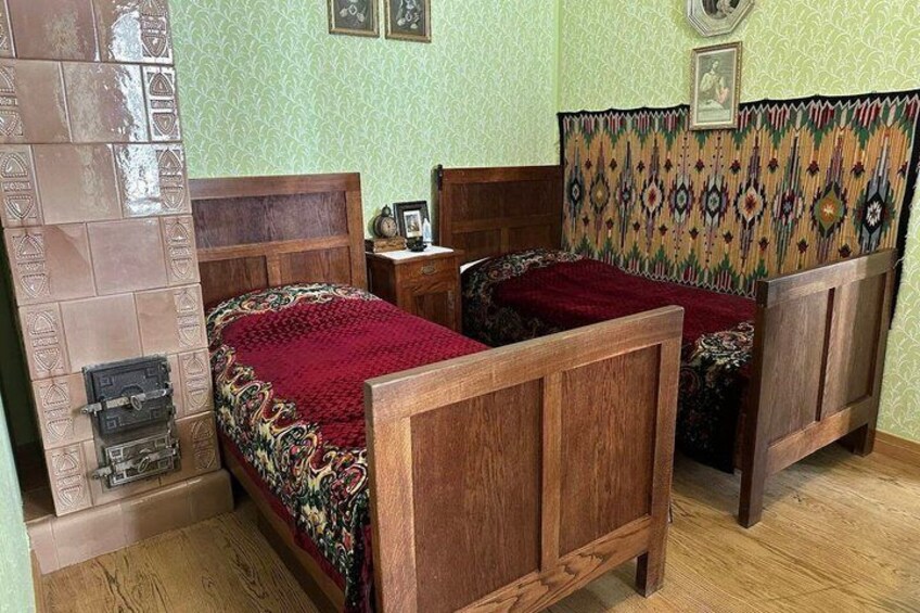 A traditional bedroom with two wooden beds, a patterned headboard, and a tiled fireplace. 5