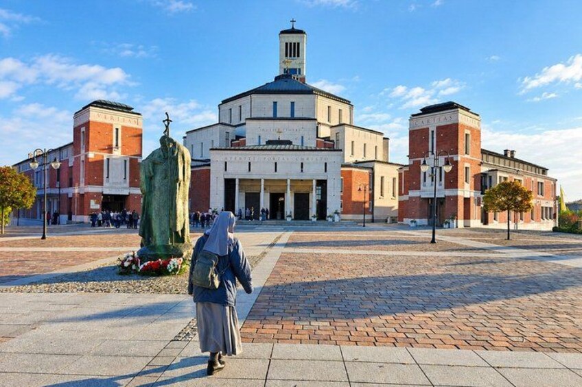 A historical building with a central dome, a statue in front, and a person walking. 5