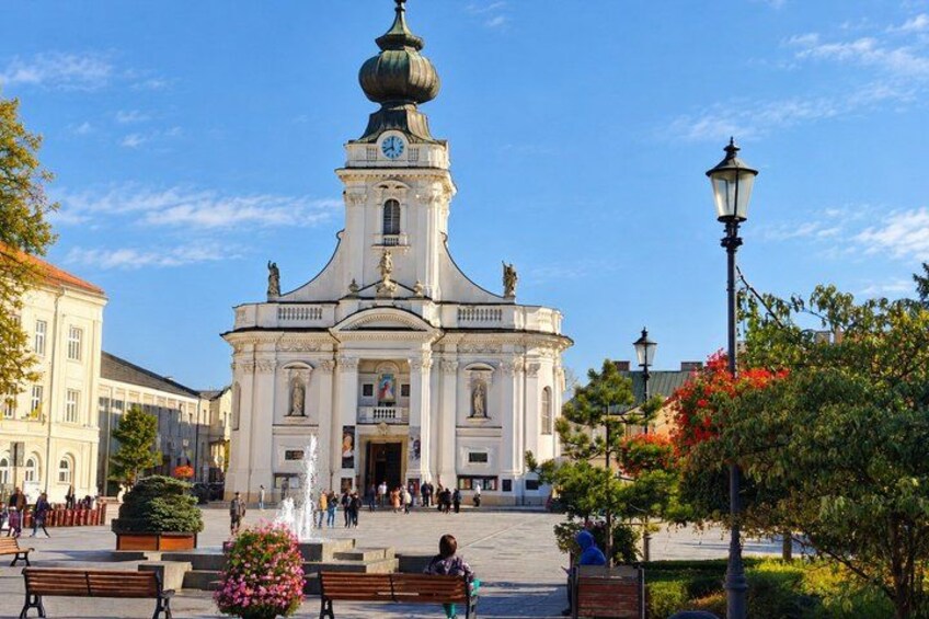 A historic building with a dome and clock tower, surrounded by a plaza with benches and a fountain. 4