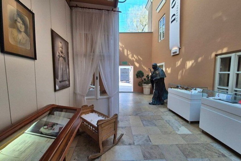 A museum interior with antique furniture, framed portraits, and a statue. 4