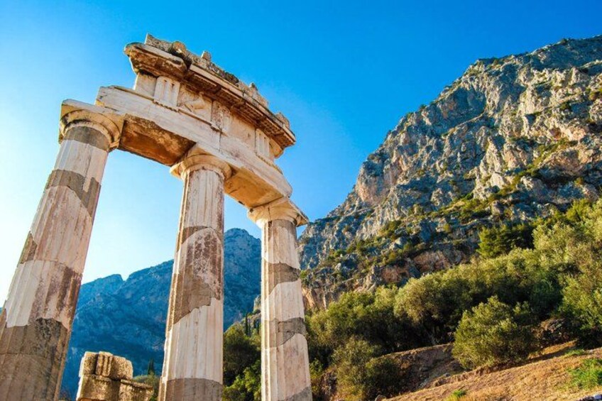 Ancient stone columns with a temple structure on top, set against a mountainous backdrop. 4
