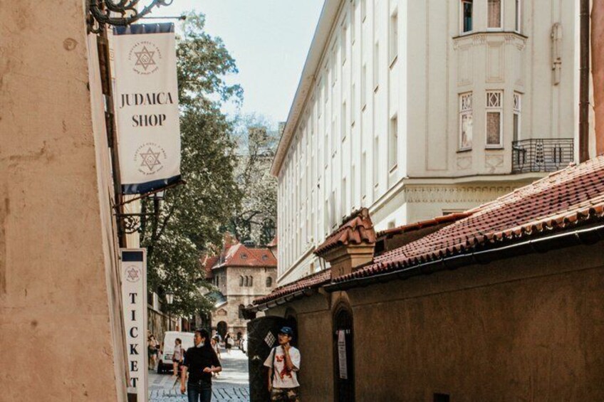 A street with a sign for 'Judaica Shop' and a ticket booth. 3