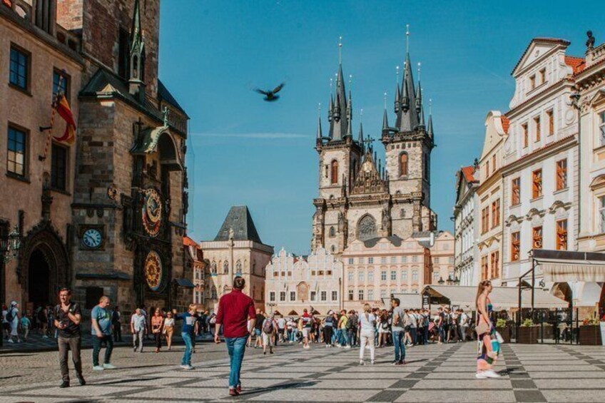A historic square with a prominent church and a clock tower, surrounded by traditional buildings. 1