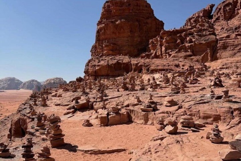 A desert landscape with red rock formations and stacked stones. 5