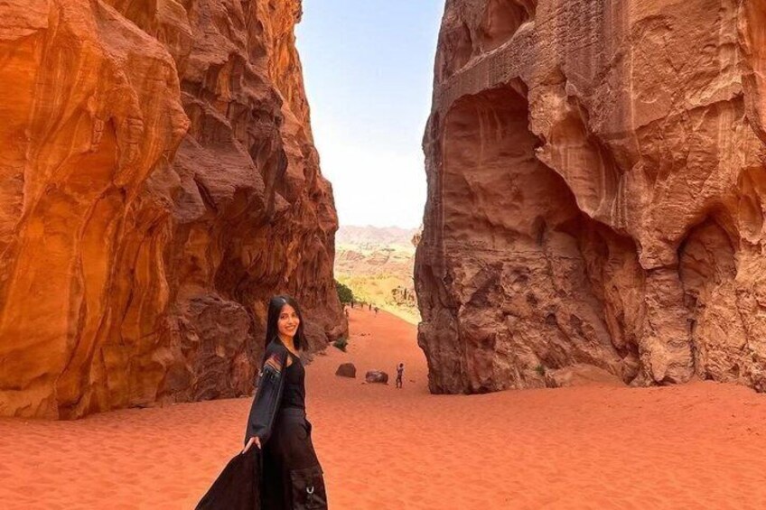 A person standing between two large rock formations with a desert landscape in the background. 2