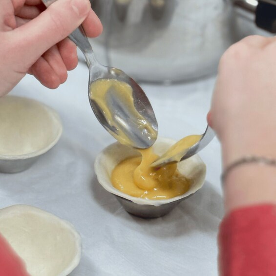 A spoon scooping a yellow sauce into a small bowl. 2