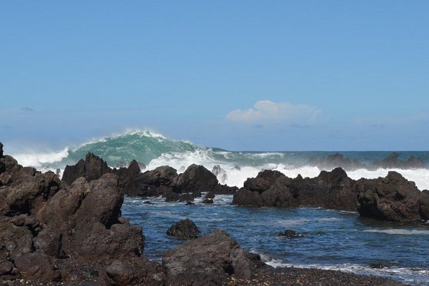 A rocky coastline with waves crashing against the rocks under a clear sky. 2