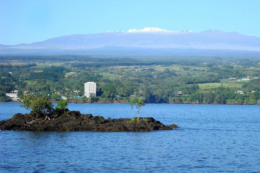 A lake with a small island, a distant mountain range, and a few buildings on the shore. 5