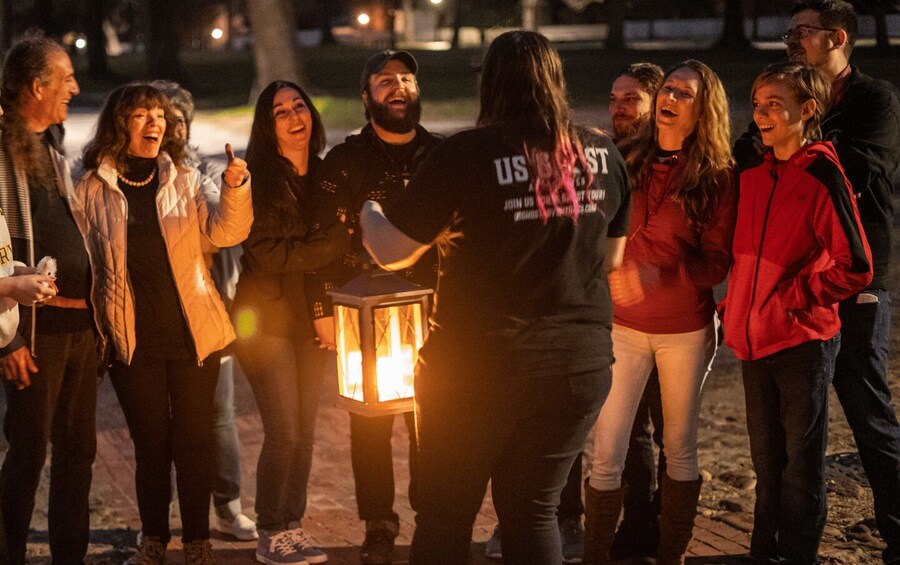 A group of people standing outdoors at night, some holding a lantern. 2