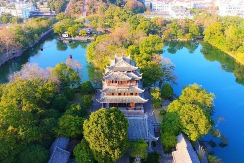 A traditional multi-tiered building surrounded by lush greenery and a calm body of water. 2