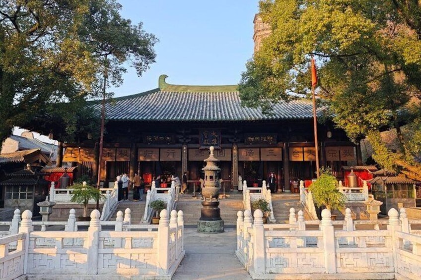 A traditional Chinese building with a tiled roof, surrounded by stone fences and a central fountain. 5