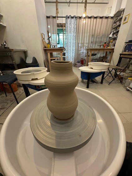 A pottery wheel with a clay vase in the center. 2