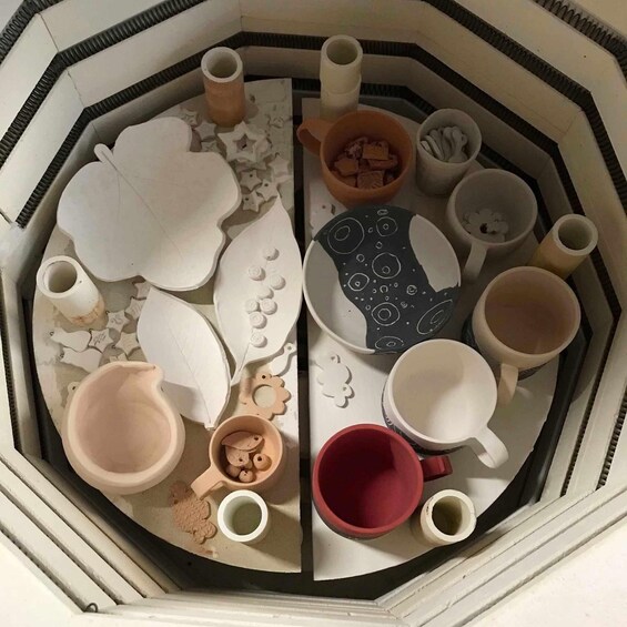 A collection of pottery and ceramics, including cups, bowls, and decorative items, arranged on a table. 5