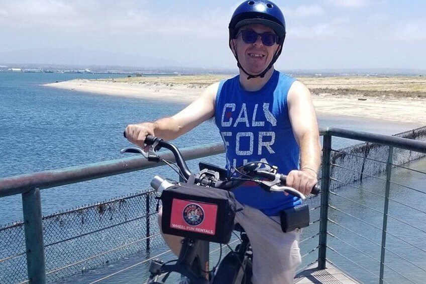 A person riding a bicycle on a bridge with a coastal landscape in the background. 4