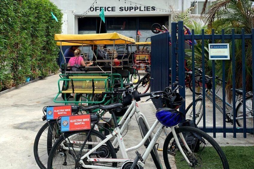 A bicycle rental station with electric bikes and a sign for office supplies. 2